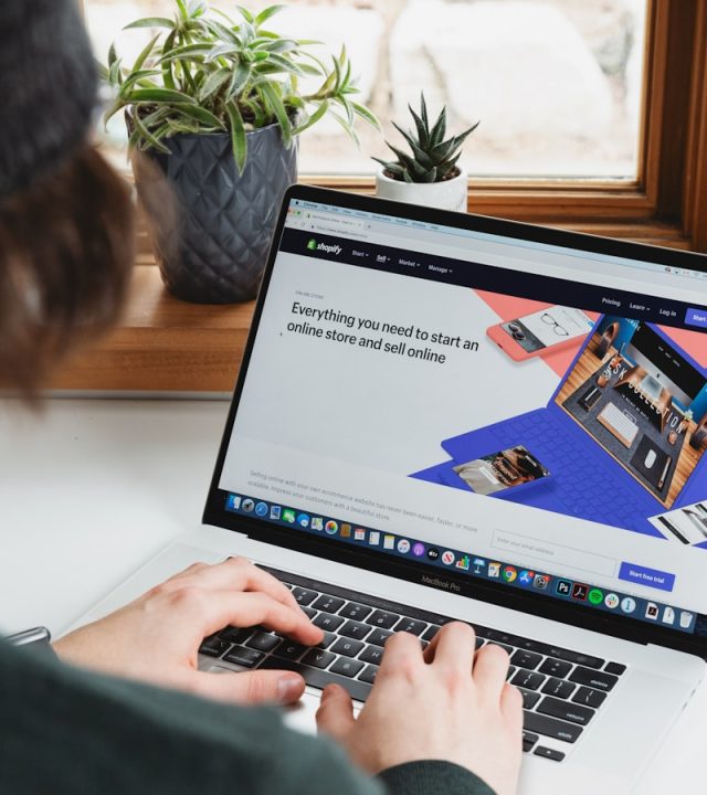 person using macbook pro on white table